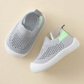Gray slip-on shoes with green accents on a beige background
