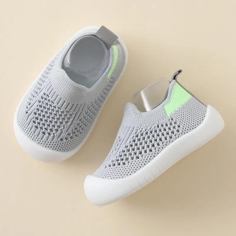 Gray slip-on shoes with green accents on a beige background