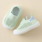 Pair of light green baby shoes on a beige background