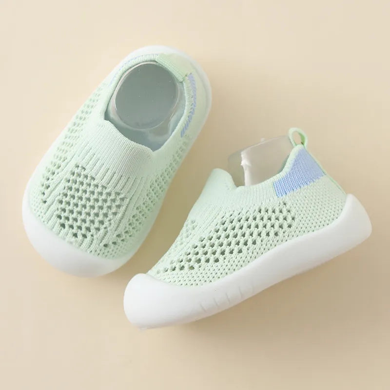 Pair of light green baby shoes on a beige background