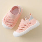 Pink baby shoes with mesh design on a beige background