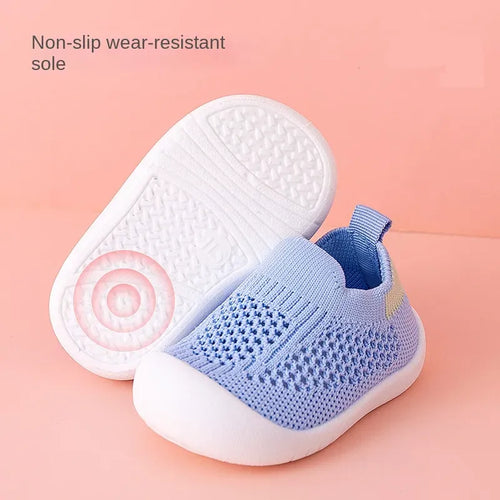 Blue baby shoe with white sole on a pink background, highlighting non-slip feature.