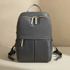 Dark gray backpack with gold zippers on a beige background