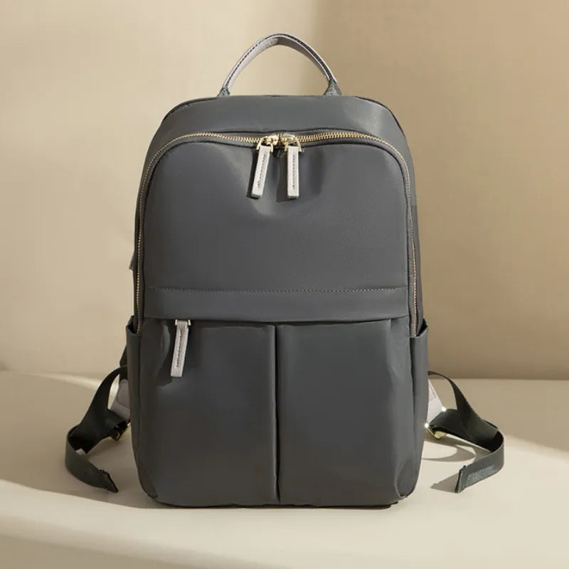 Dark gray backpack with gold zippers on a beige background