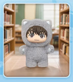 Gray plush toy with hood and character design in a library setting
