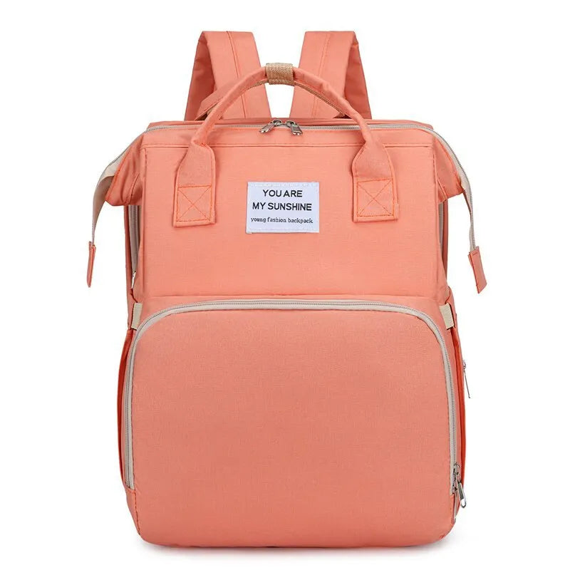 Peach multifunction portable diaper backpack with white accents on a white background