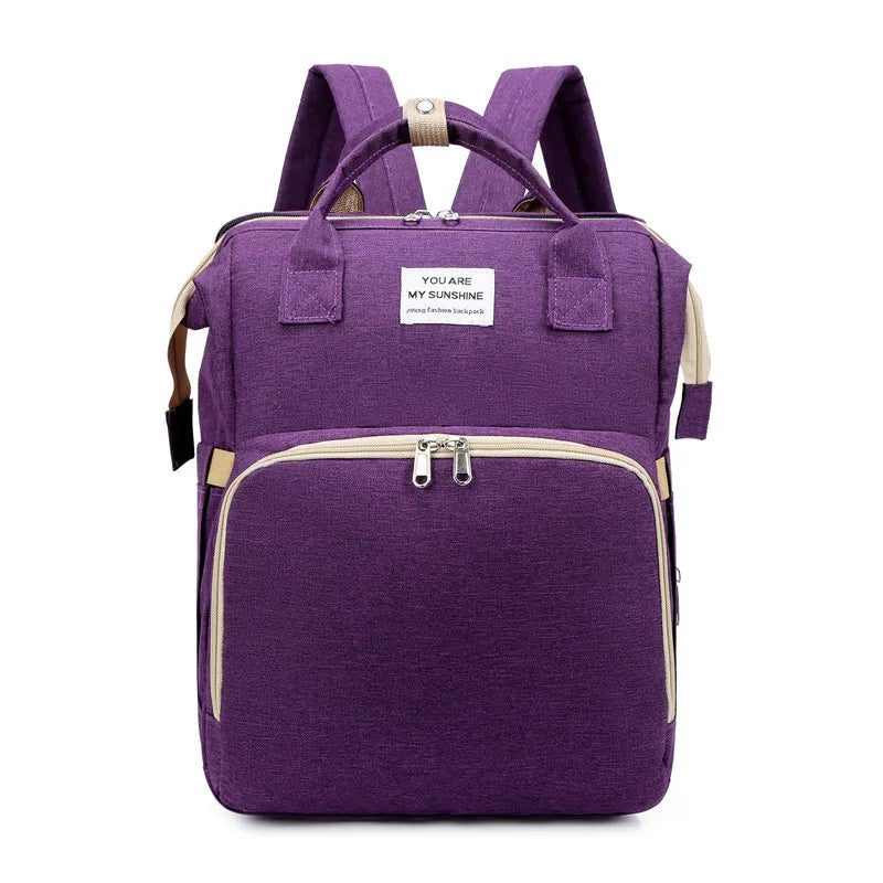 Purple multifunction portable diaper backpack with white accents on a white background