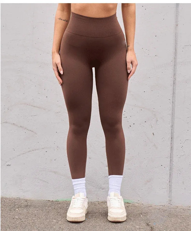 Person wearing brown high waist v-back leggings against a neutral background