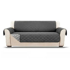 Gray quilted waterproof sofa cover on a beige sofa against a white background