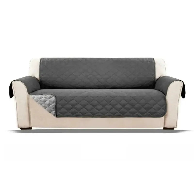Gray quilted waterproof sofa cover on a beige sofa against a white background