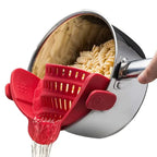 Pasta being drained with a red silicone strainer from a steel pot on white background