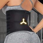 Person wearing a black waist trainer  standing against a blurred indoor background. View of back